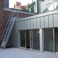 TRANSFORMATION: Zinc clad exterior of 6th floor apartment with terrace and skylight above.
