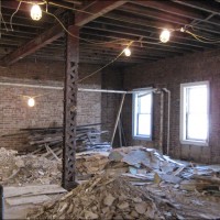 Removal of damaged plaster and lath reveals  original masonry, wood joists and steel frame.